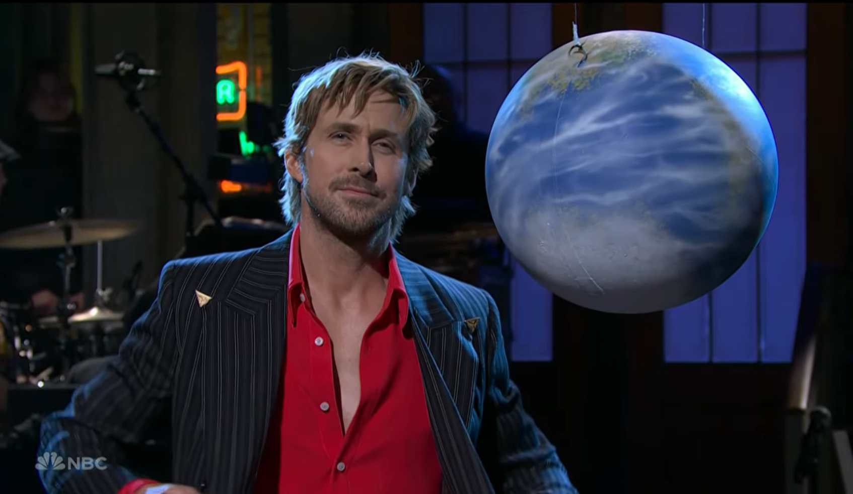 Ryan Gosling looking at a model of Earth.