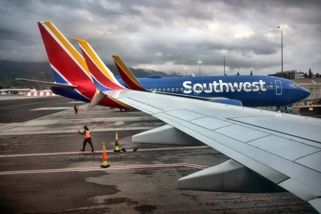 A Southwest Airlines ground crew member guides a plane out of the terminal.