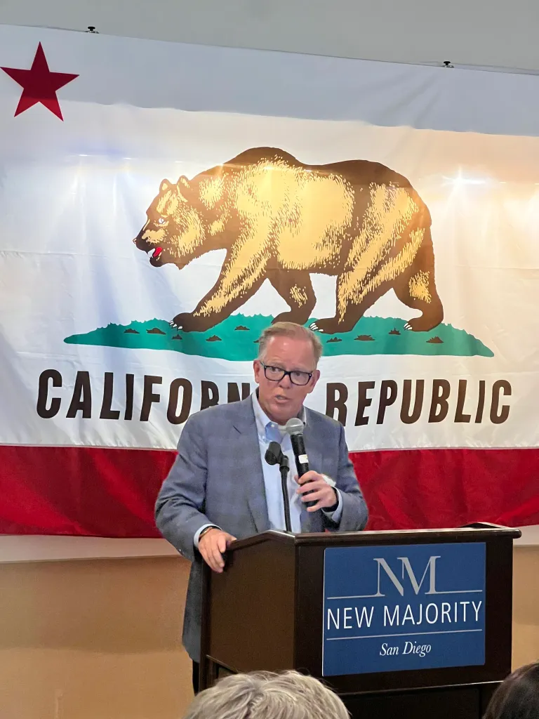 Herb Morgan, California state controller candidate, speaks at a podium with a California Republic flag behind him.