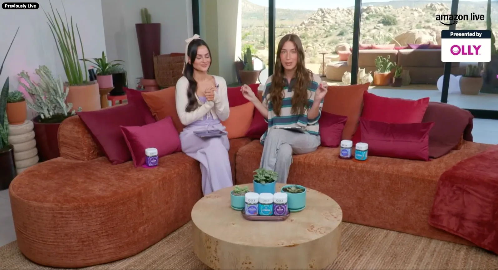 Two women on a rust-colored couch with red pillows, presenting Olly vitamins and supplements.