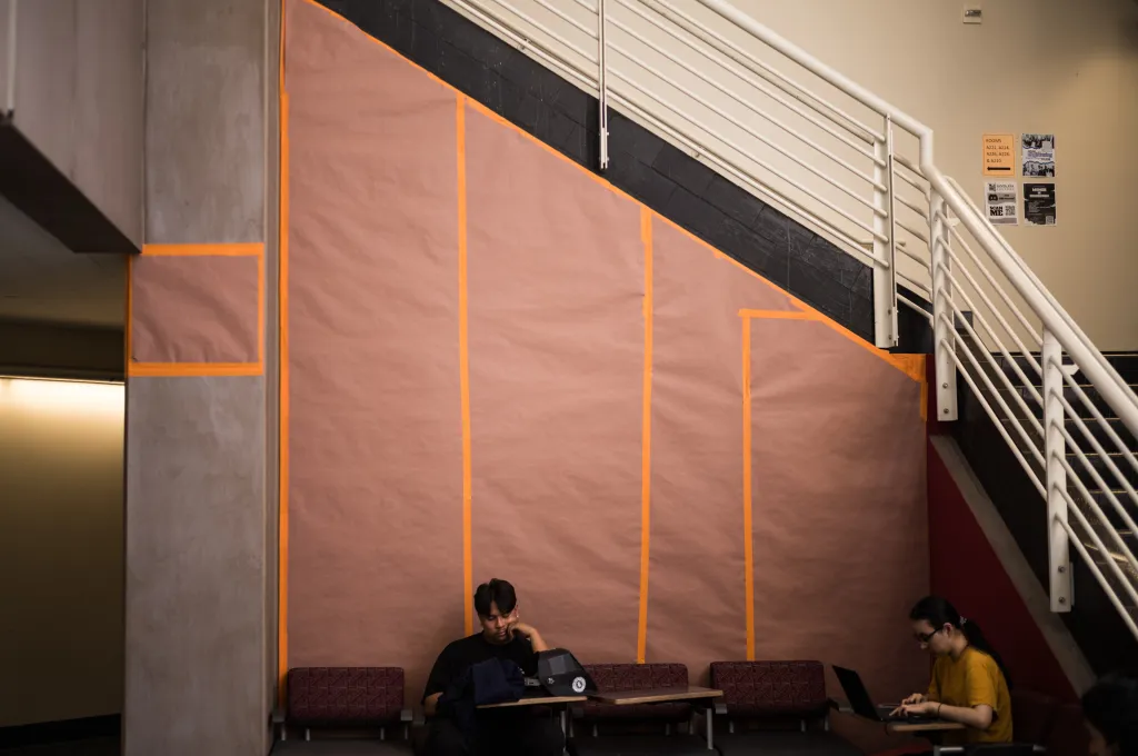 Students sit in front of a covered mural of Cesar Chavez at Santa Ana College.