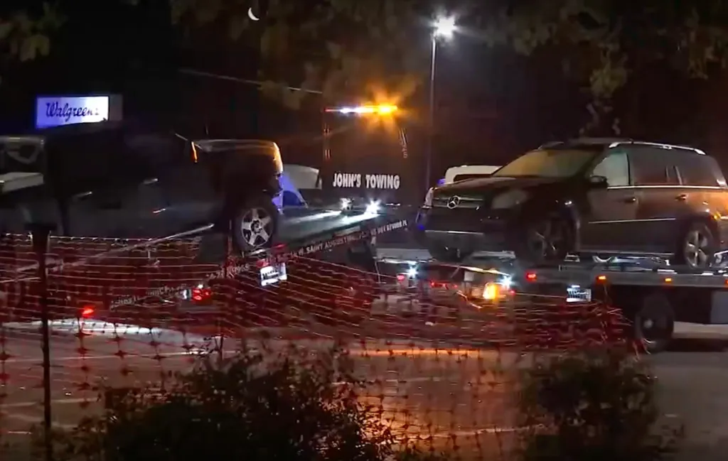 Two dark colored SUVs on flatbed tow trucks, with the back of a Walgreens sign visible in the background.