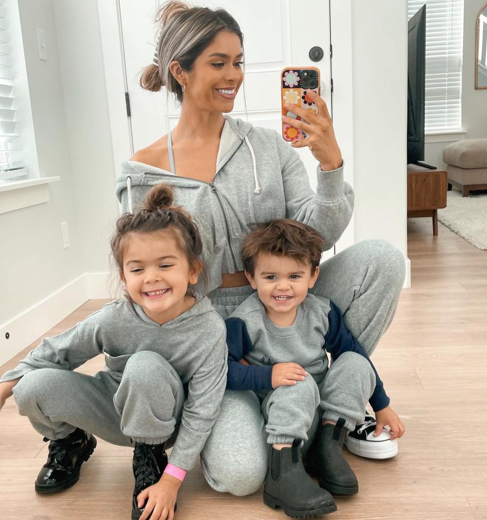 Taylor Frankie Paul posing for a selfie with her two children, all wearing gray sweat suits.