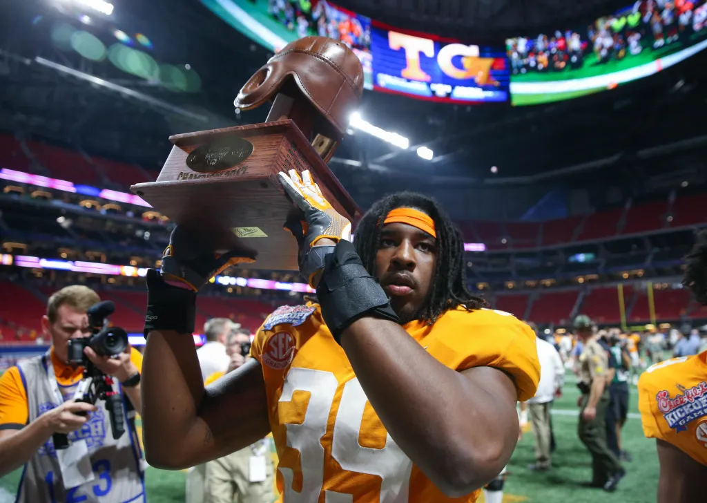 Tennessee Volunteers defensive lineman Kendal Vickers holding up the old leather helmet trophy.