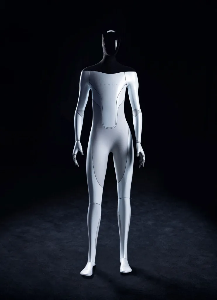 A white and black humanoid robot prototype from Tesla stands against a black background.