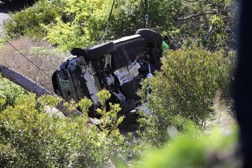 Tiger Woods' Genesis GV80 overturned in a rollover crash, being lifted from the scene by a crane.
