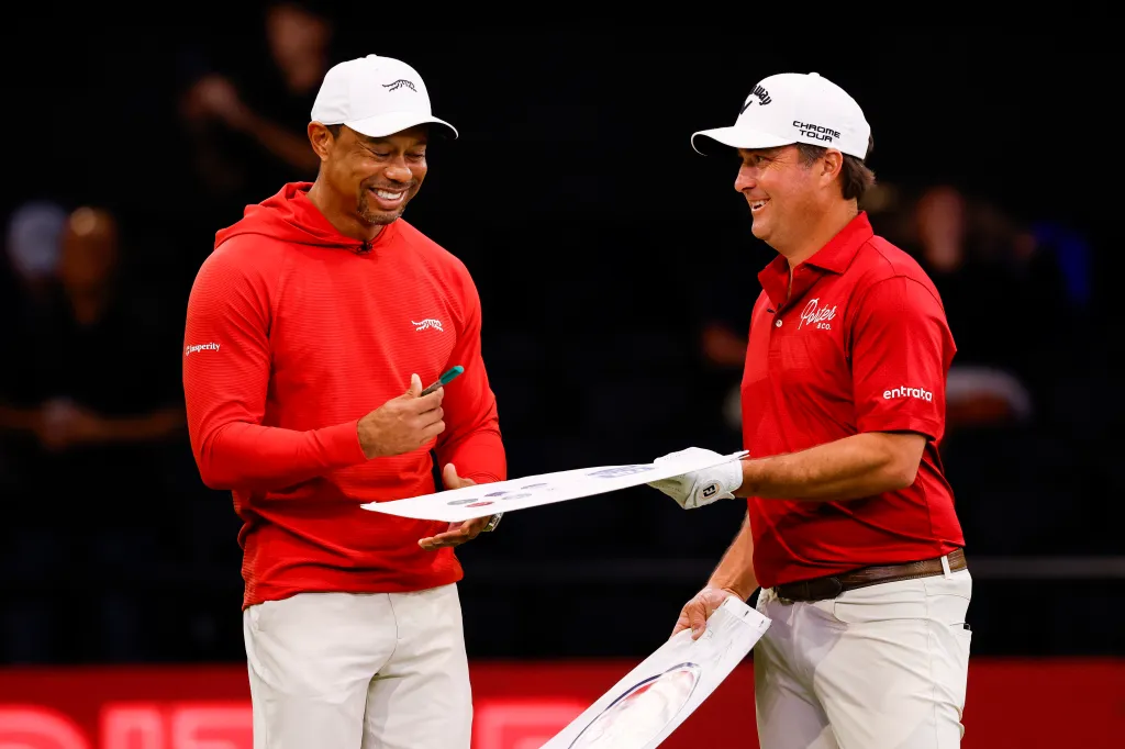 Tiger Woods signing autographs with Kevin Kisner before a match.