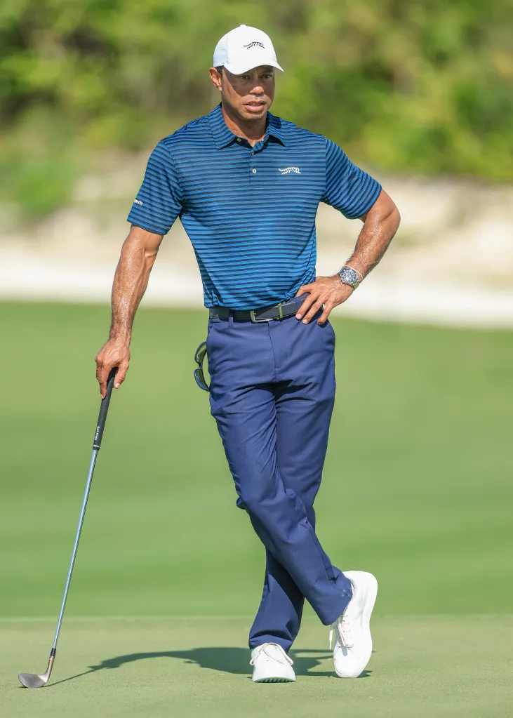 Tiger Woods holds a golf club while watching a pro-am.