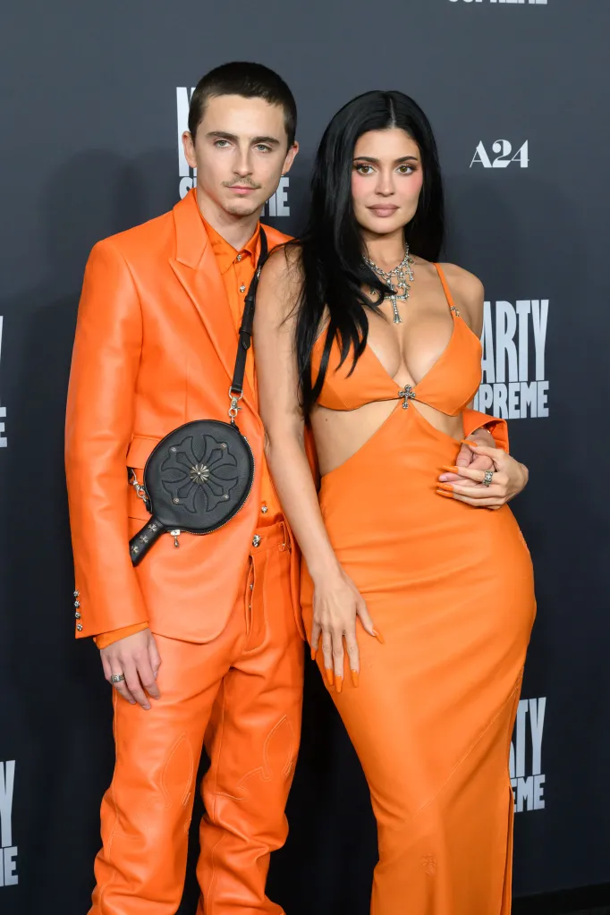 Timothée Chalamet, in an orange suit, and Kylie Jenner, in an orange dress, posing at the