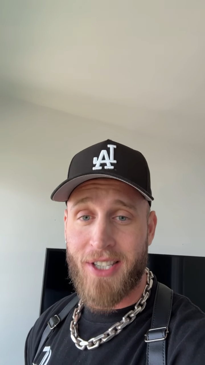 Chet Hanks, Tom Hanks' son, in a black hat with an LA logo, a black t-shirt, and a large silver chain, revealing that he is stuck in Colombia without his US passport.