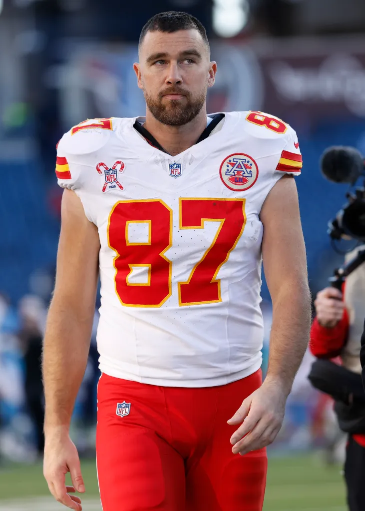 Travis Kelce, wearing a white Kansas City Chiefs jersey with the number 87, walks off the field after a defeat.