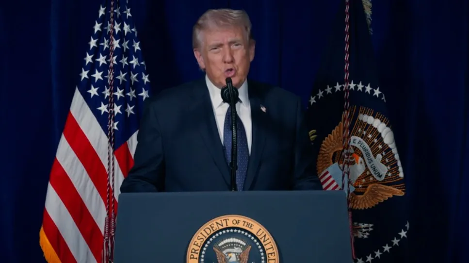 Donald Trump speaking at a podium with US flags in the background.