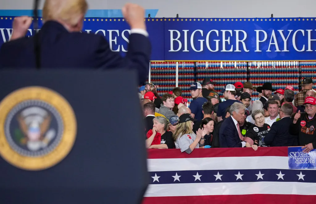 President Donald Trump reacts as Dr. Mehmet Oz joins first responders assisting a woman who collapsed during his speech.