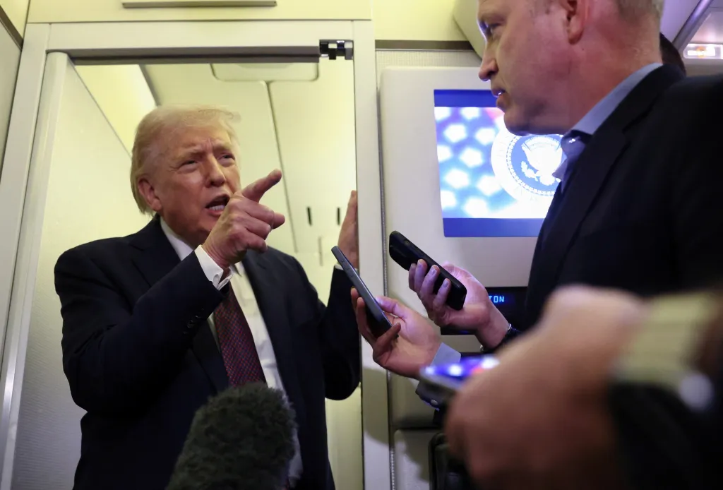 President Donald Trump speaks to reporters aboard Air Force One.
