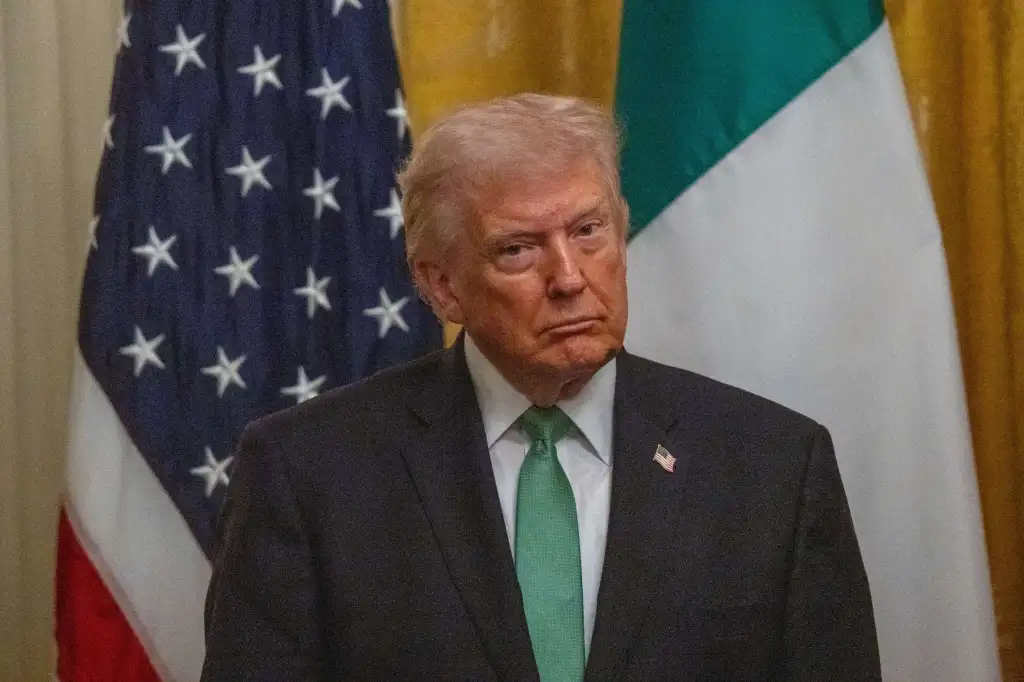 Donald Trump, wearing a green tie and US flag pin, stands between the American and Irish flags.