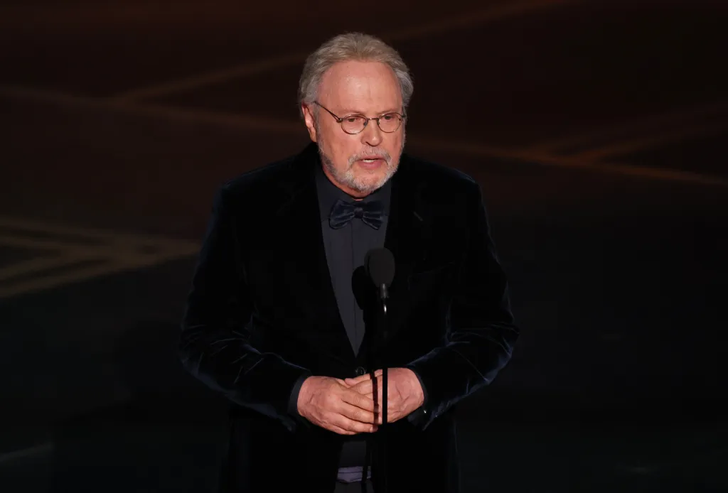 Billy Crystal speaking onstage at the Academy Awards.