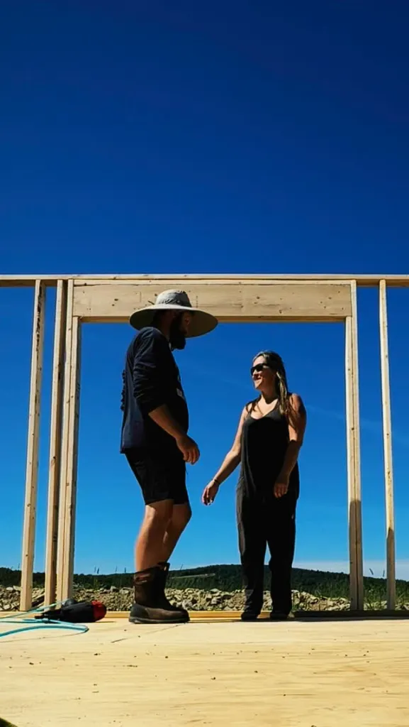 Victoria and Tyler Neidhardt standing in a doorway of a tiny home under construction.