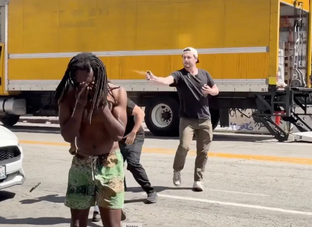 A man pepper-spraying another man who is covering his face.