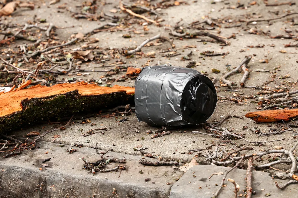 Unexploded homemade explosive device on the ground next to a piece of wood.