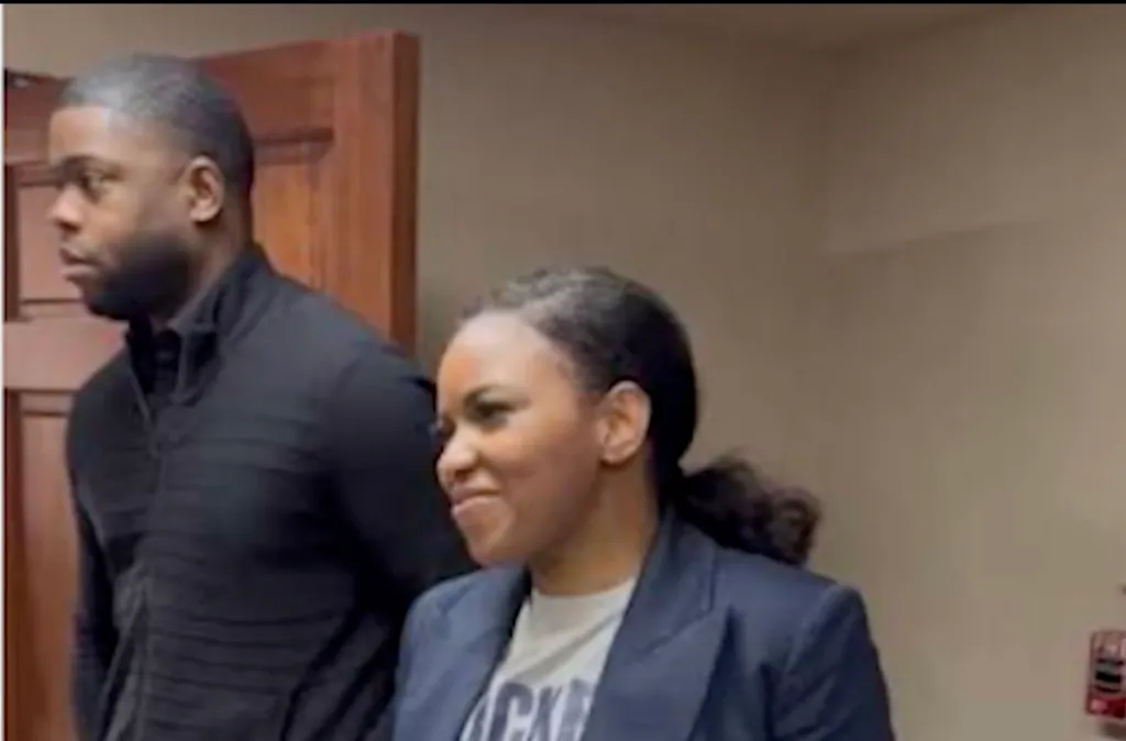 A man in a black long-sleeved shirt and a woman in a dark blazer over a light T-shirt.