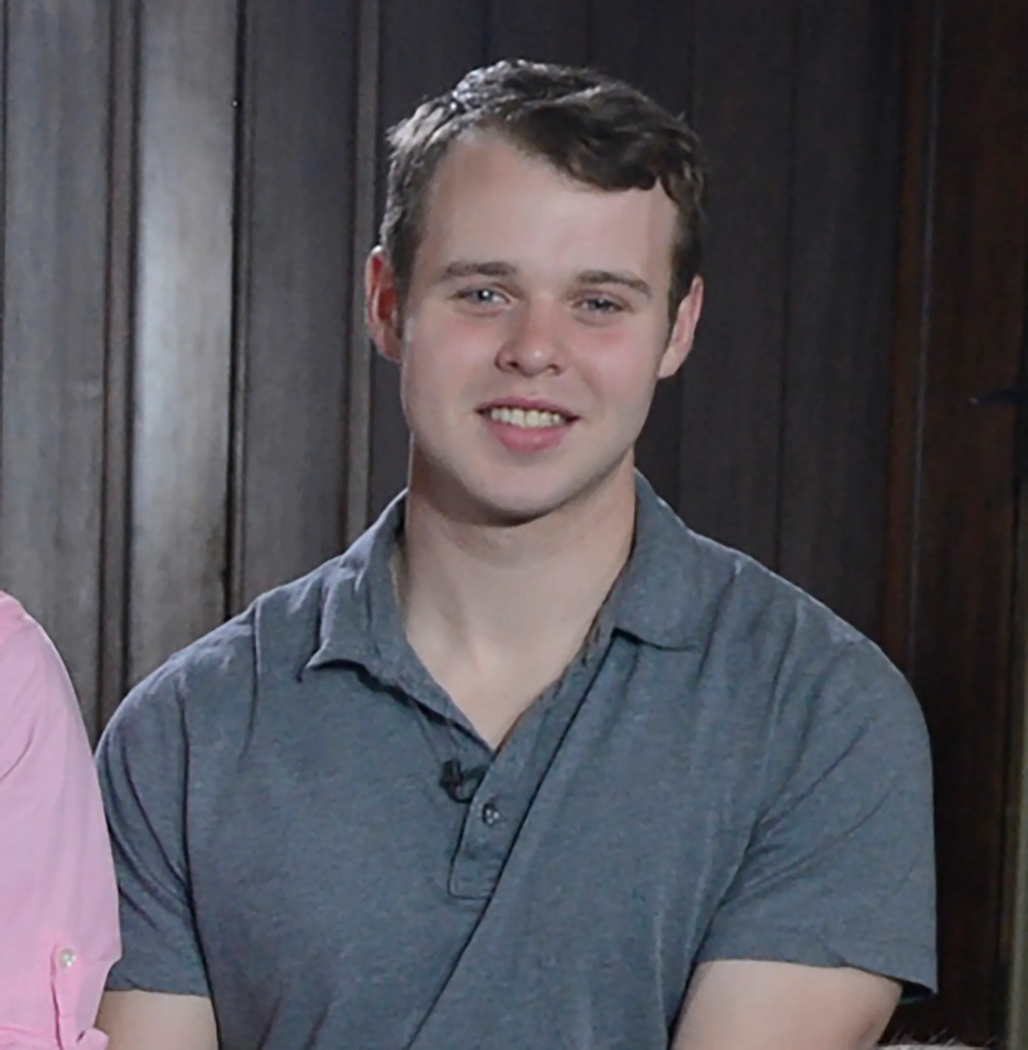 Josiah Duggar smiling in a grey polo shirt.