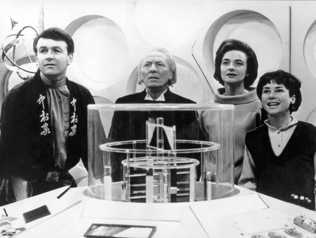 From left, William Russell, William Hartnell, Jacqueline Hill, and Carole Ann Ford stand next to the Doctor Who console.