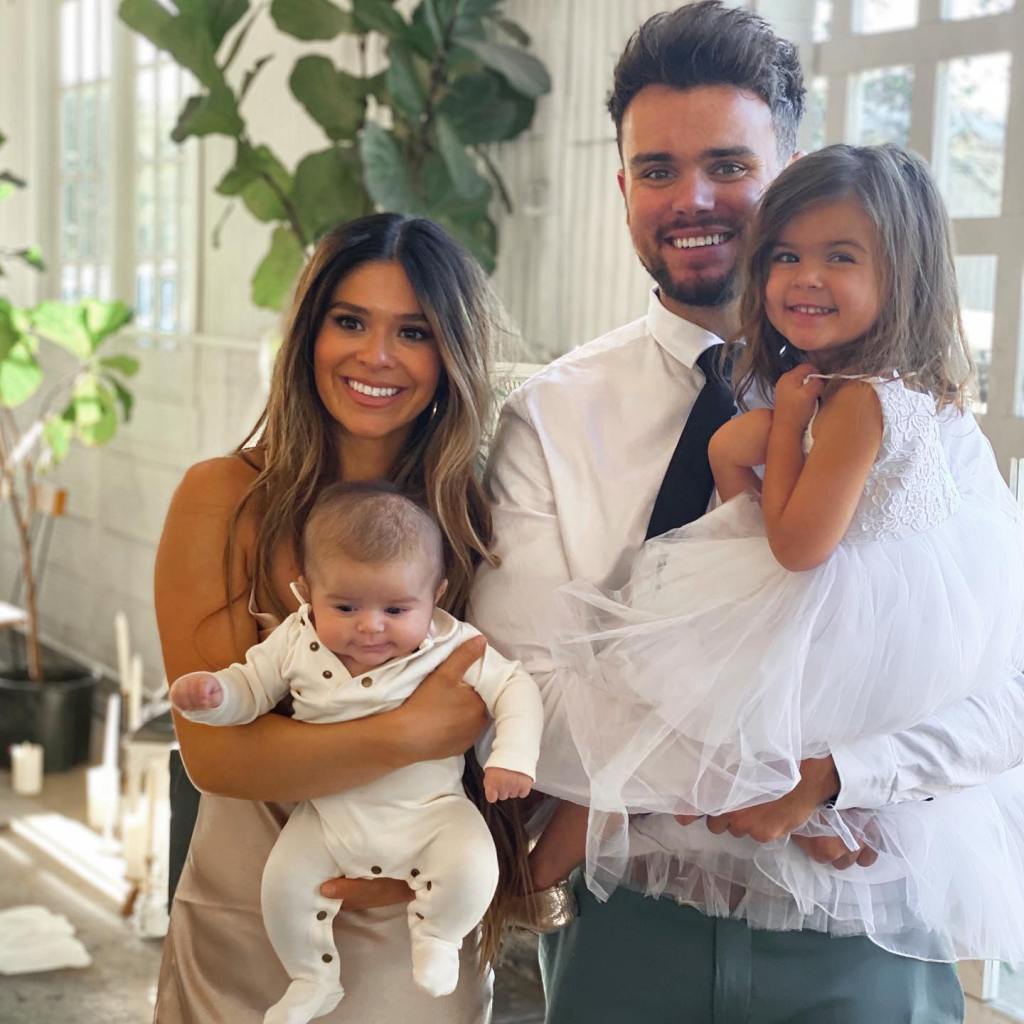 A smiling couple holding their two young children.