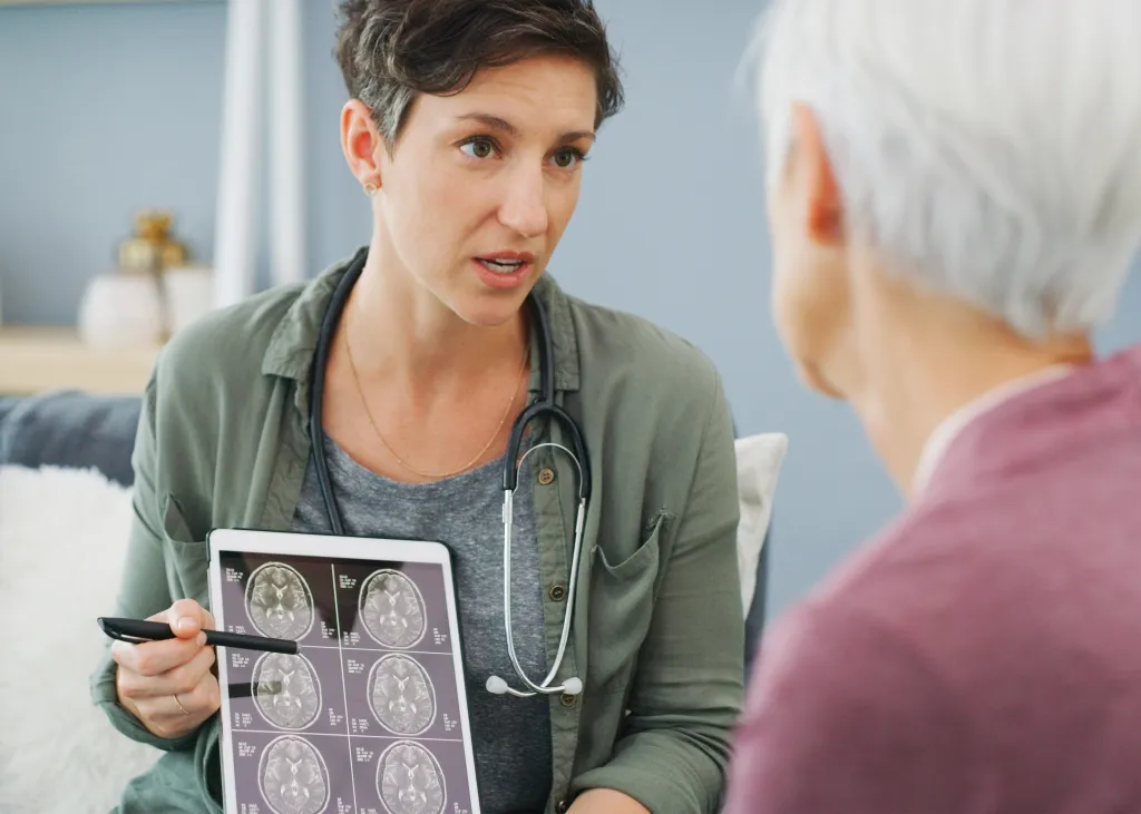 A doctor shows a patient a brain scan on a digital tablet.