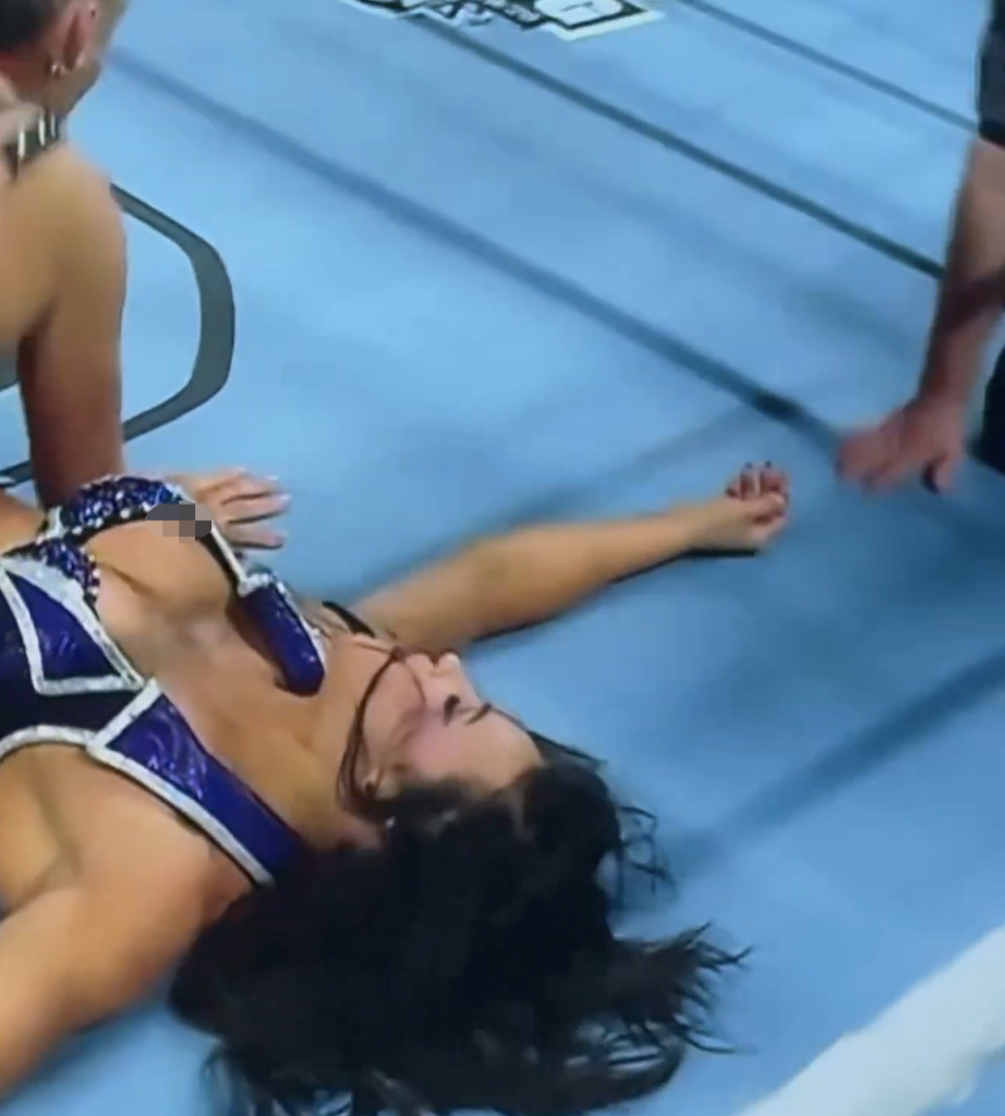 WWE wrestler Kiana James lies on her back on the blue wrestling mat.