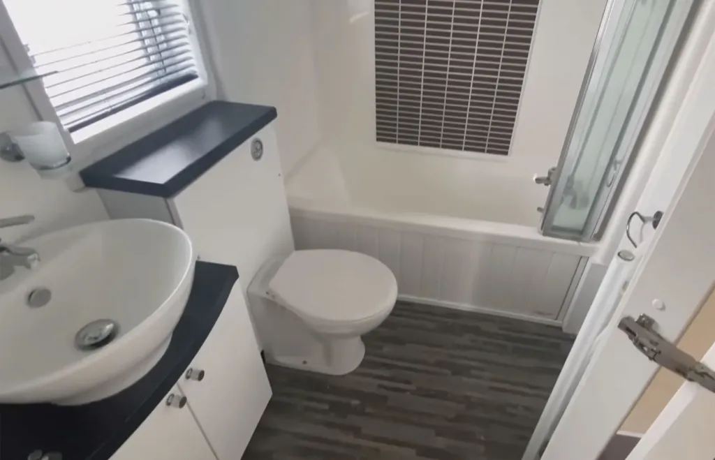 A compact, bright white bathroom with a toilet, sink, and bathtub.