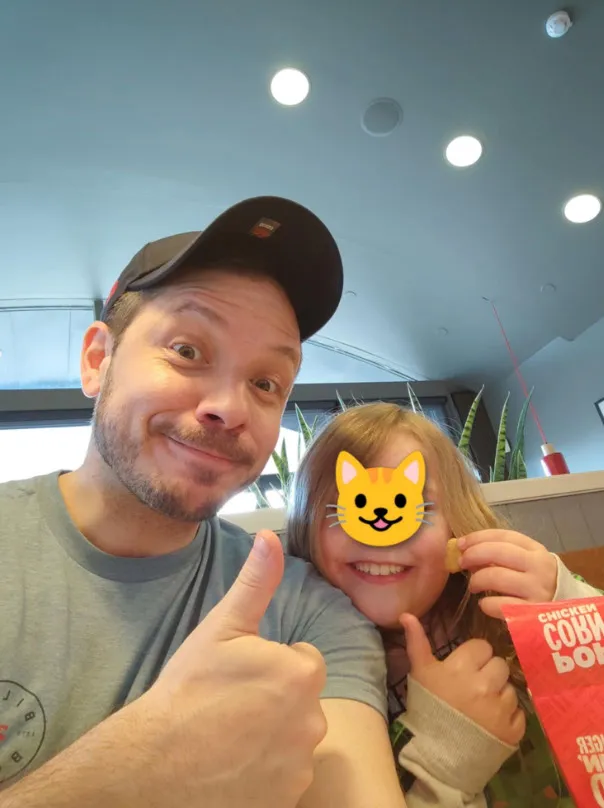 A man and a young child, both giving thumbs up.