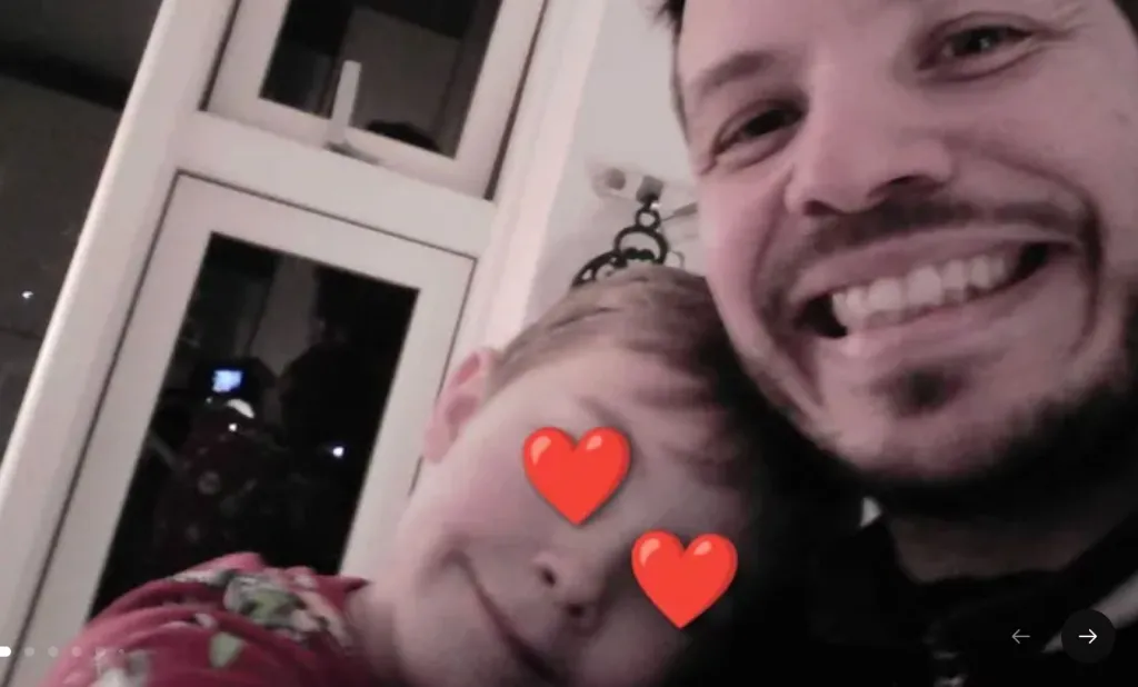 A father and child smiling, with red hearts covering the child's eyes.