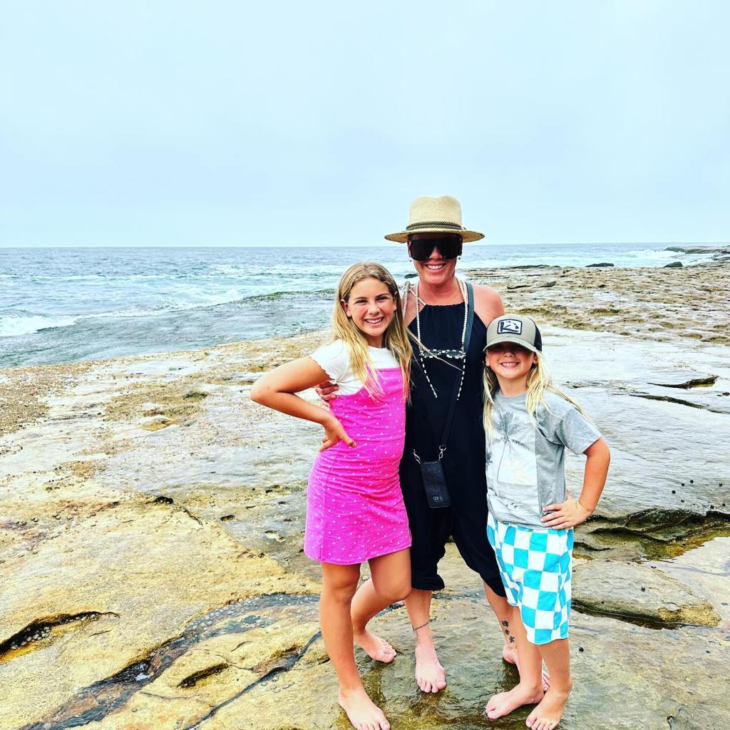 Pink and her children, Willow and Jameson, pose on a rocky beach.