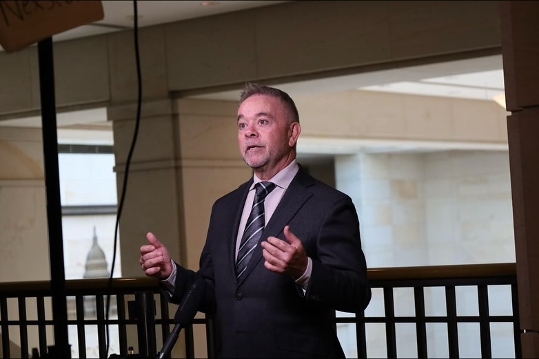 A man in a suit speaks at a podium.