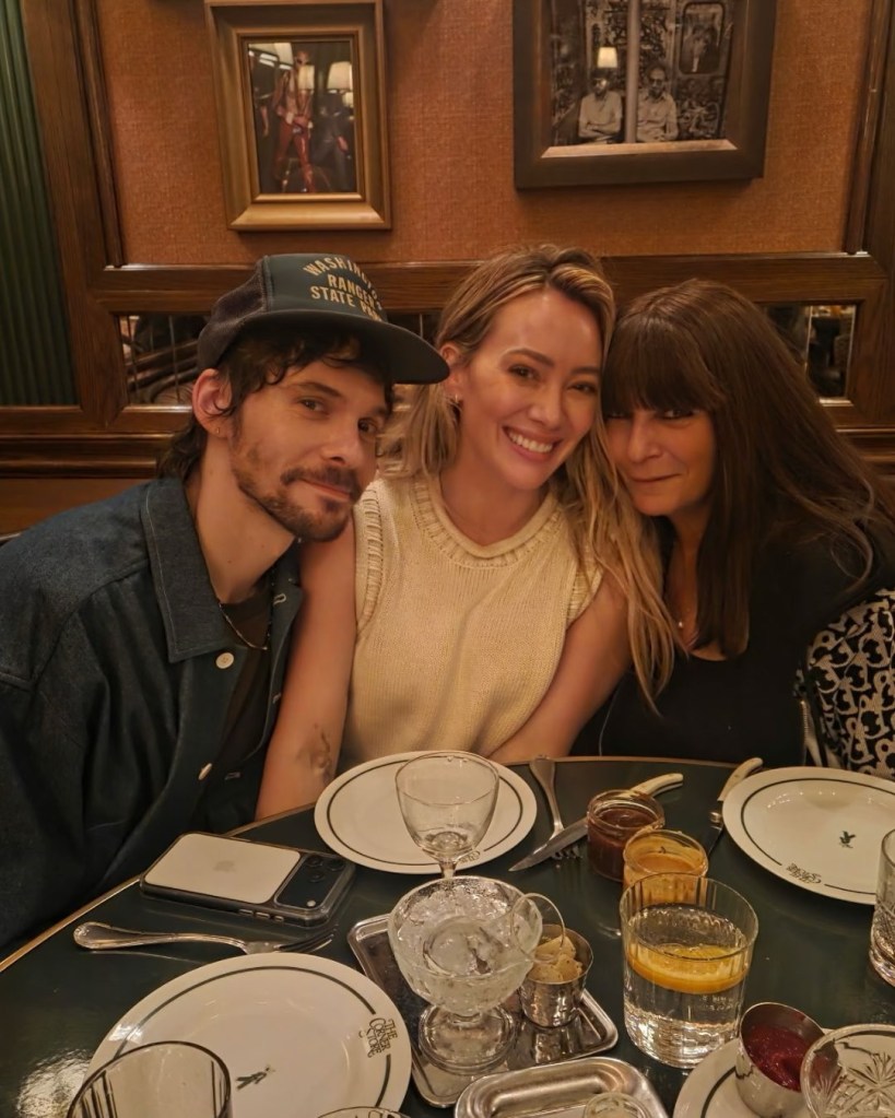 Hilary Duff posing with two people at a dining table.