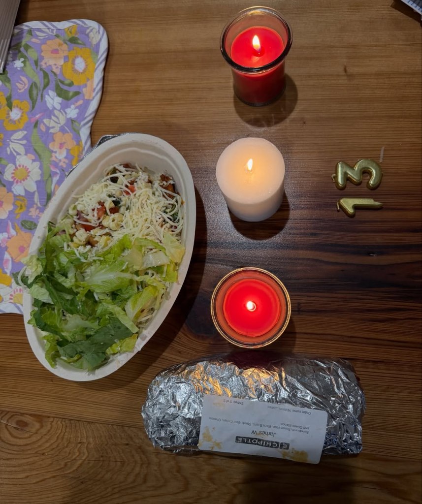 Chipotle burrito bowl and wrapped burrito on a table with lit candles and a 