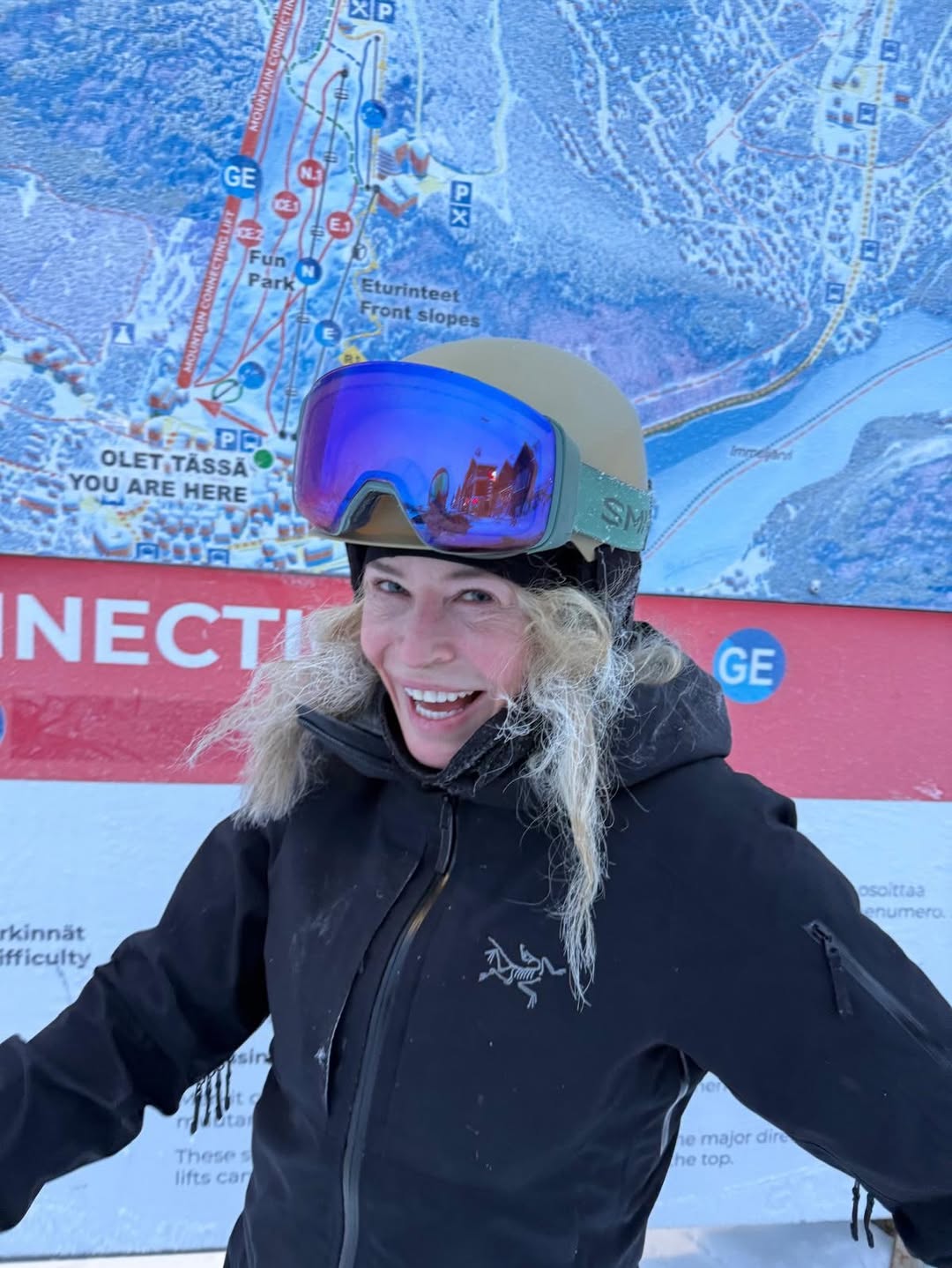 Chelsea Handler smiling in ski gear in front of a ski resort map.