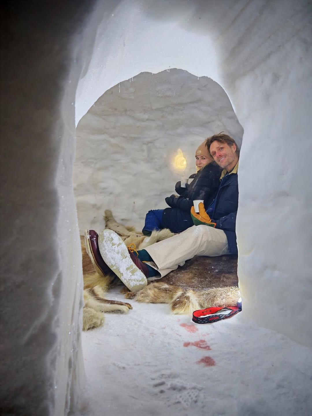 Chelsea Handler and a man sitting inside an igloo.