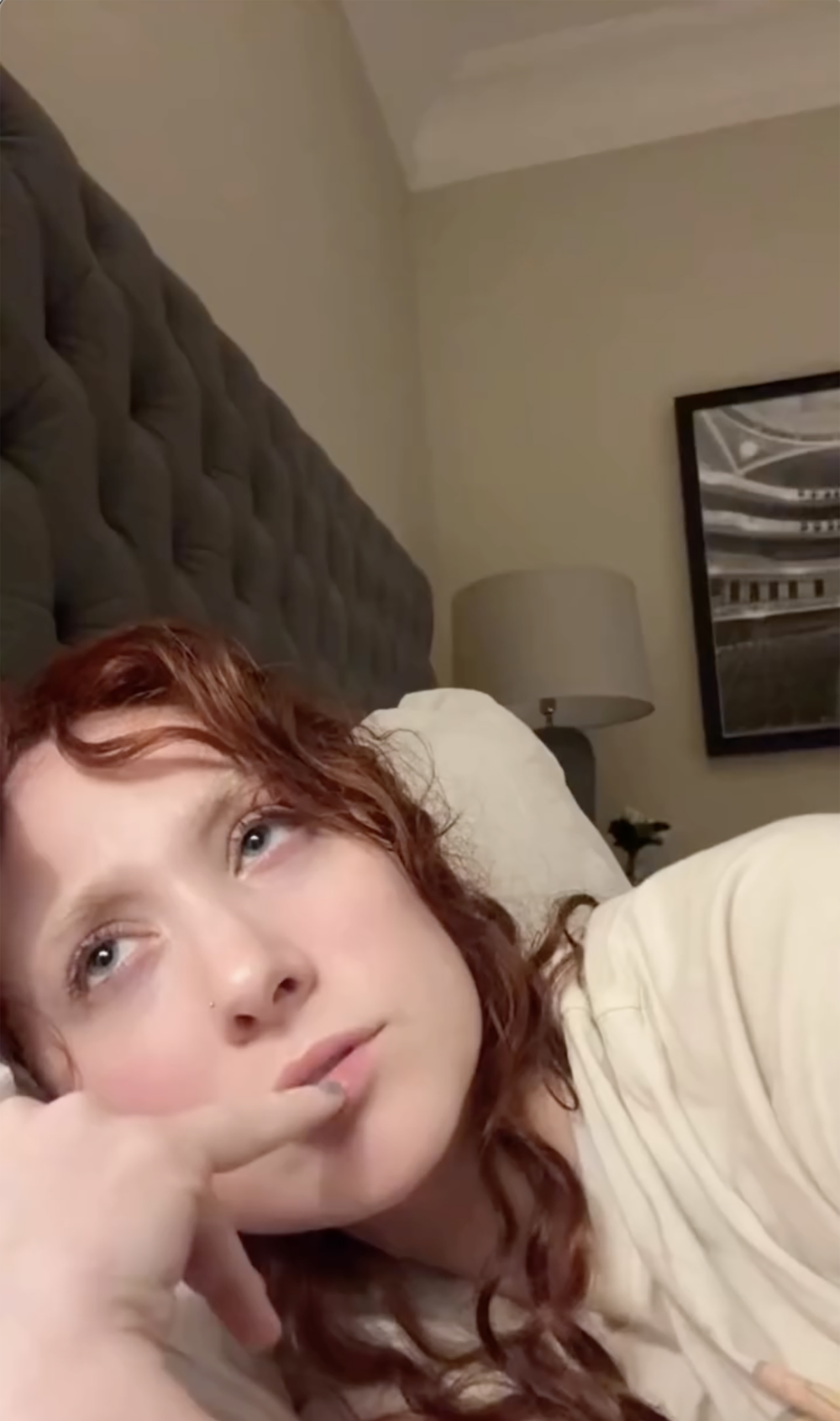 Chappell Roan lying in bed looking up, her finger touching her lip.