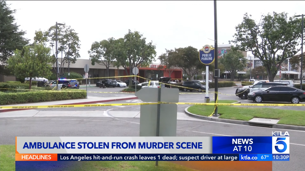 Crime scene with police cars and yellow tape in a public parking area.