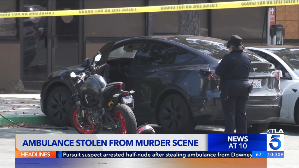 Police officer at a crime scene with a black Tesla, motorcycle, and yellow caution tape.