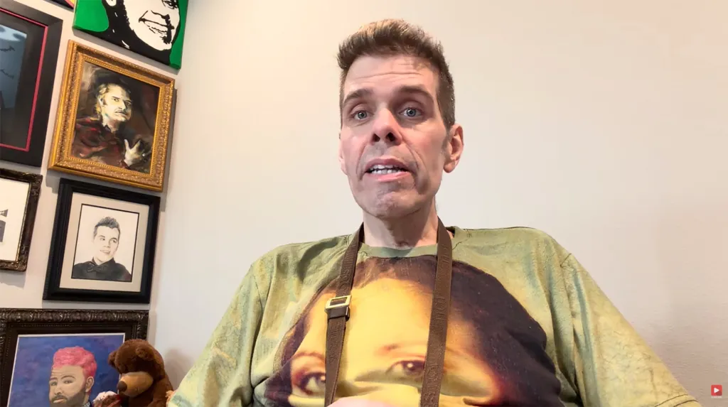 Perez Hilton speaking to the camera in a room with framed art.