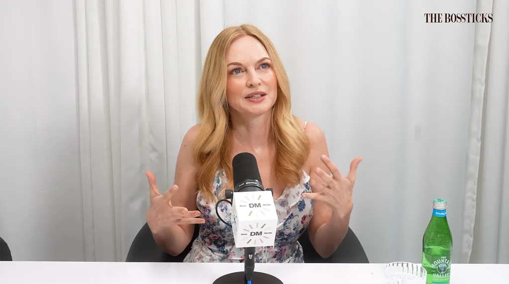 Heather Graham speaks into a microphone, gesturing with her hands.