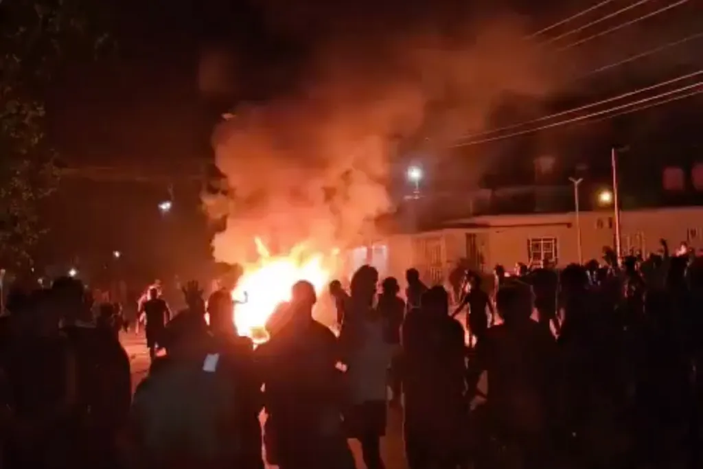 Nighttime photo of a large fire burning in a street in Cuba, surrounded by a crowd of people.