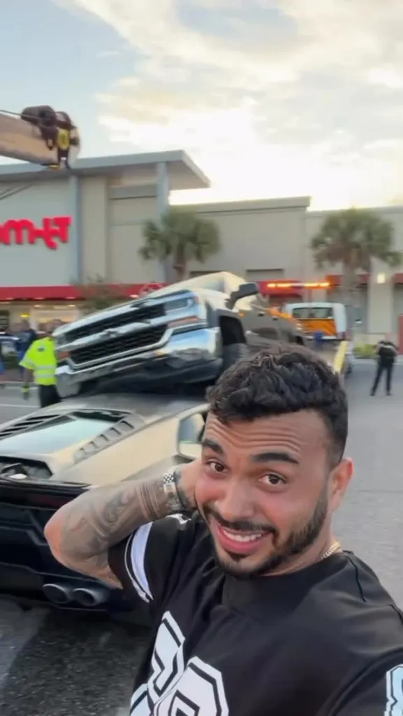Ramon Ferrer takes a selfie in front of his wrecked Lamborghini with a pickup truck on top of it.