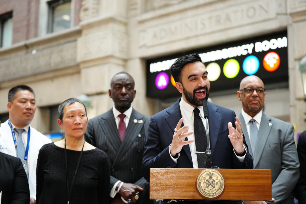 New York City Mayor Zohran Mamdani speaks at a podium about the city's first Outposted Therapeutic Housing Unit at NYC Health + Hospitals/Bellevue.