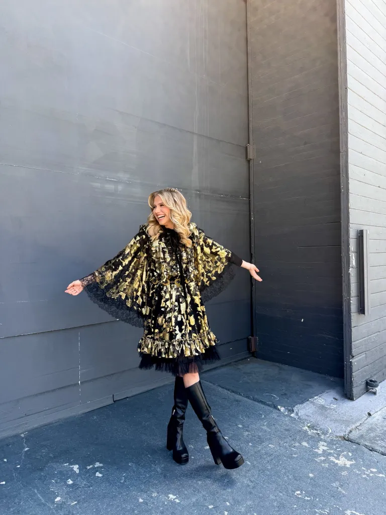 Hannah Harper in a black and gold dress with black boots.