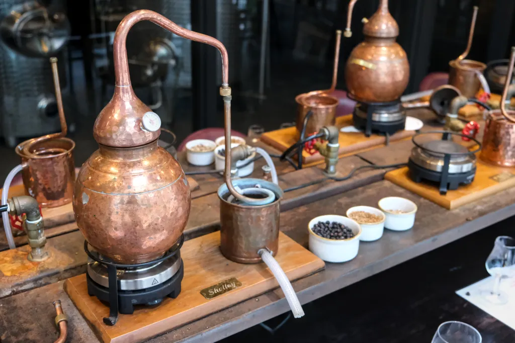Small copper stills and distilling equipment arranged on a decorated table.