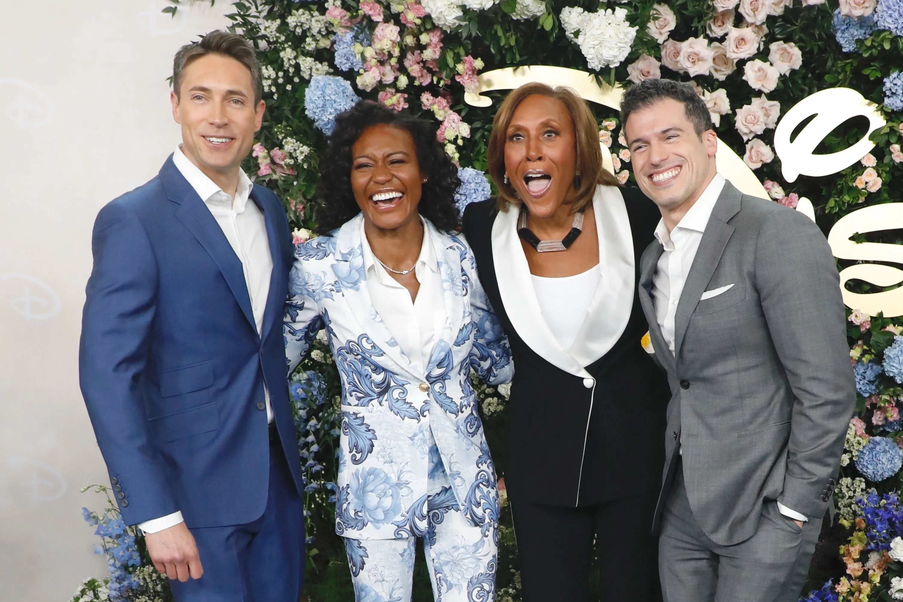 Whit Johnson, Janai Norman, Robin Roberts, and Gio Benitez smiling in front of a floral backdrop.
