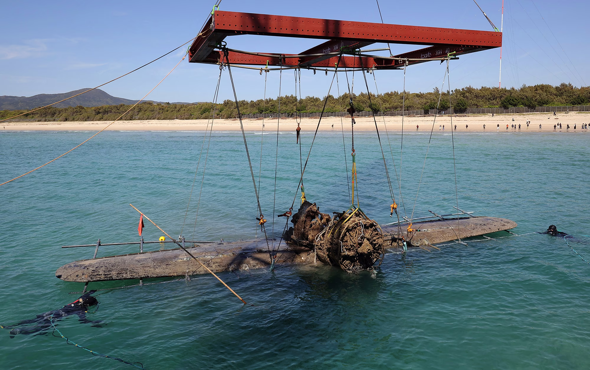 Parts of a badly-deteriorated WWII-era Japanese fighter plane are raised from the ocean.